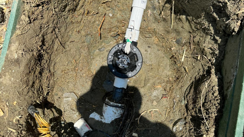 Sprinkler system valve assembly uncovered in soil during repair