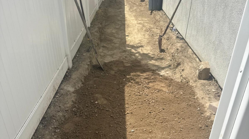 Side yard dirt path leveled and prepared for paver installation