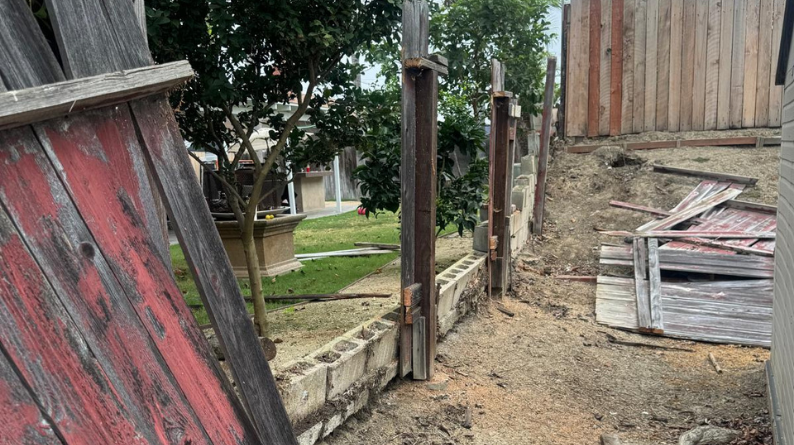 Old fence removal with broken panels and exposed posts on a hillside