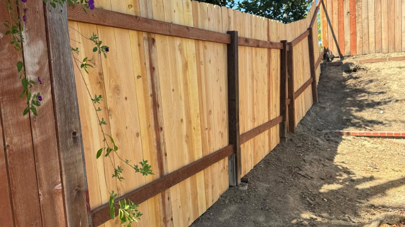 Newly built wooden fence line bordering a dirt slope