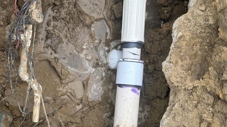PVC irrigation pipe repair in a trench with new couplers and damp soil