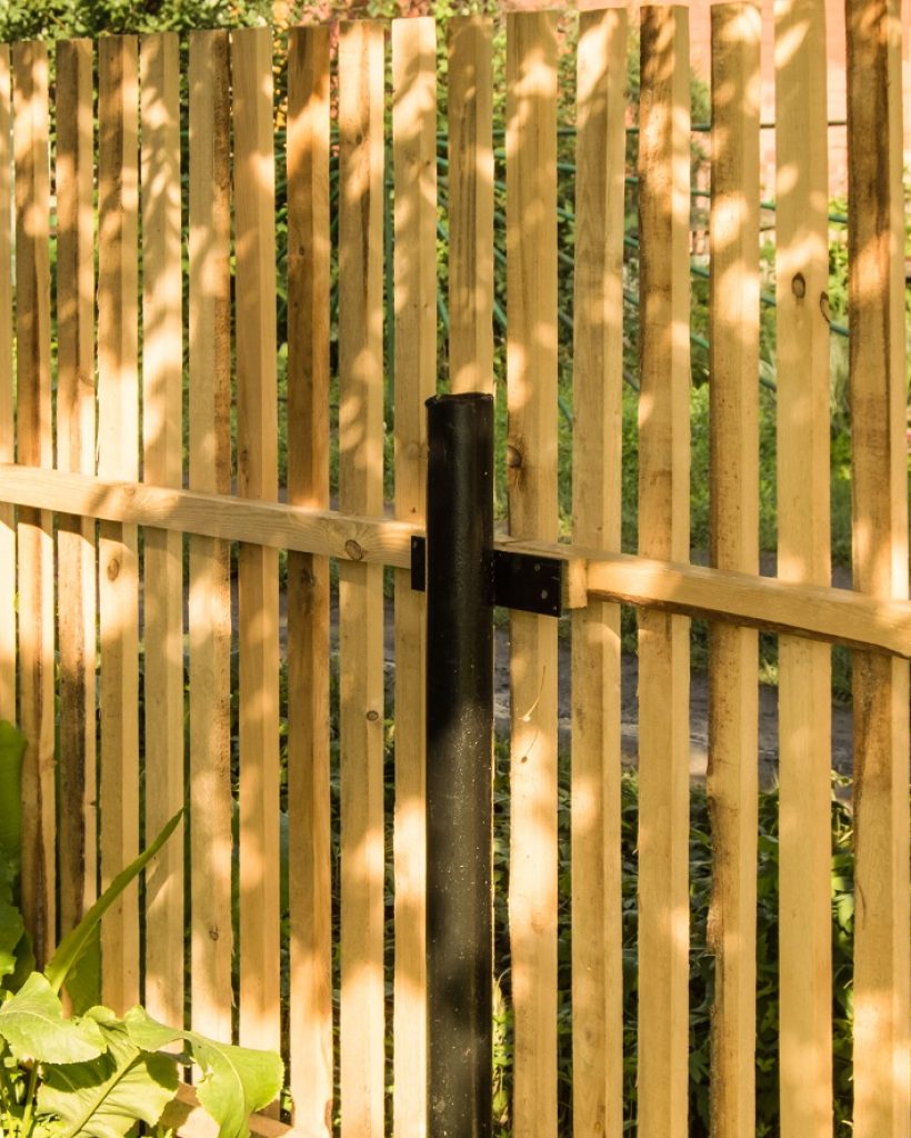 New picket fence and black metal poles, built in the garden.